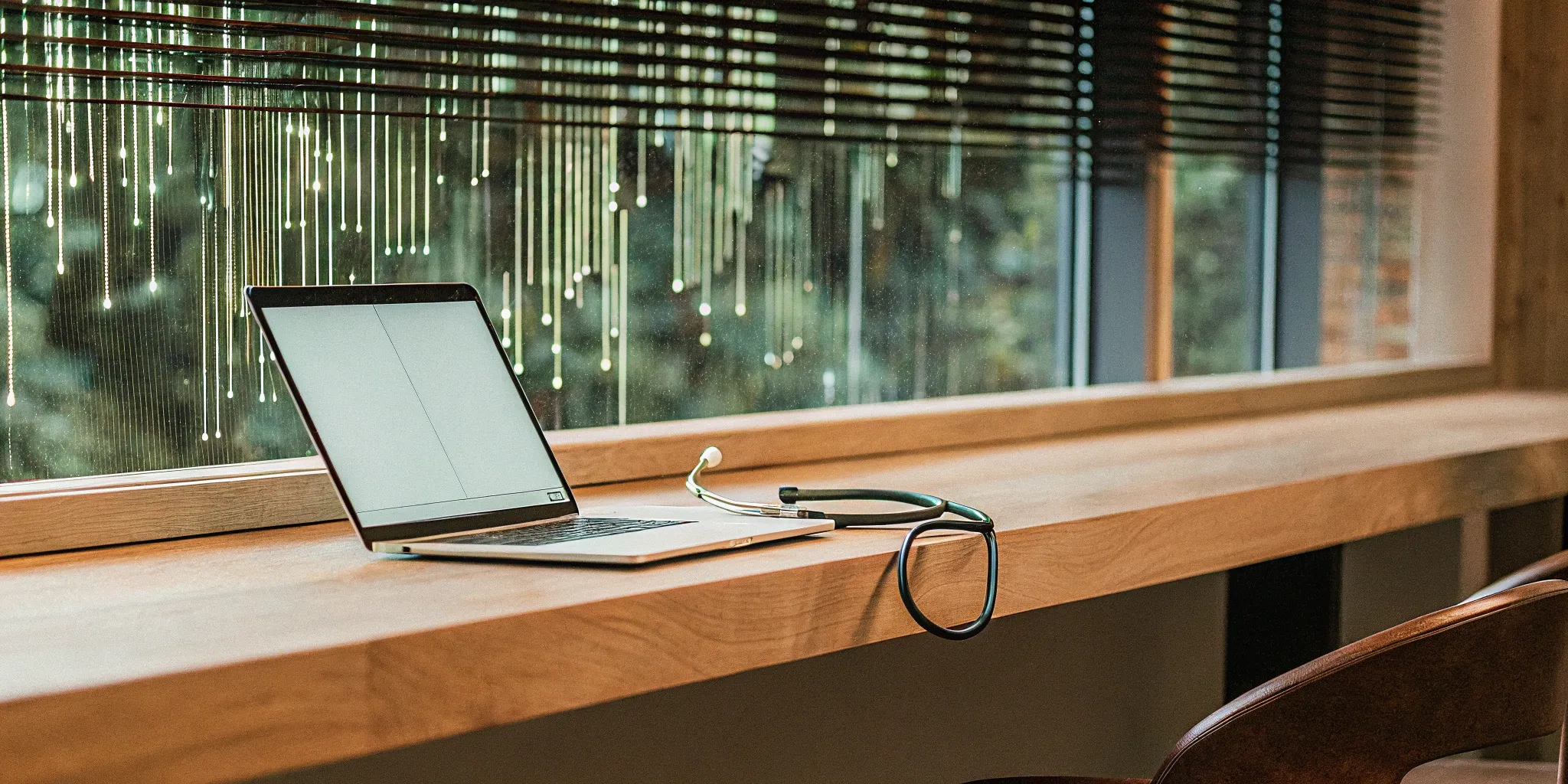 A laptop and stethoscope on a desk as an employer determines if they must offer health insurance.